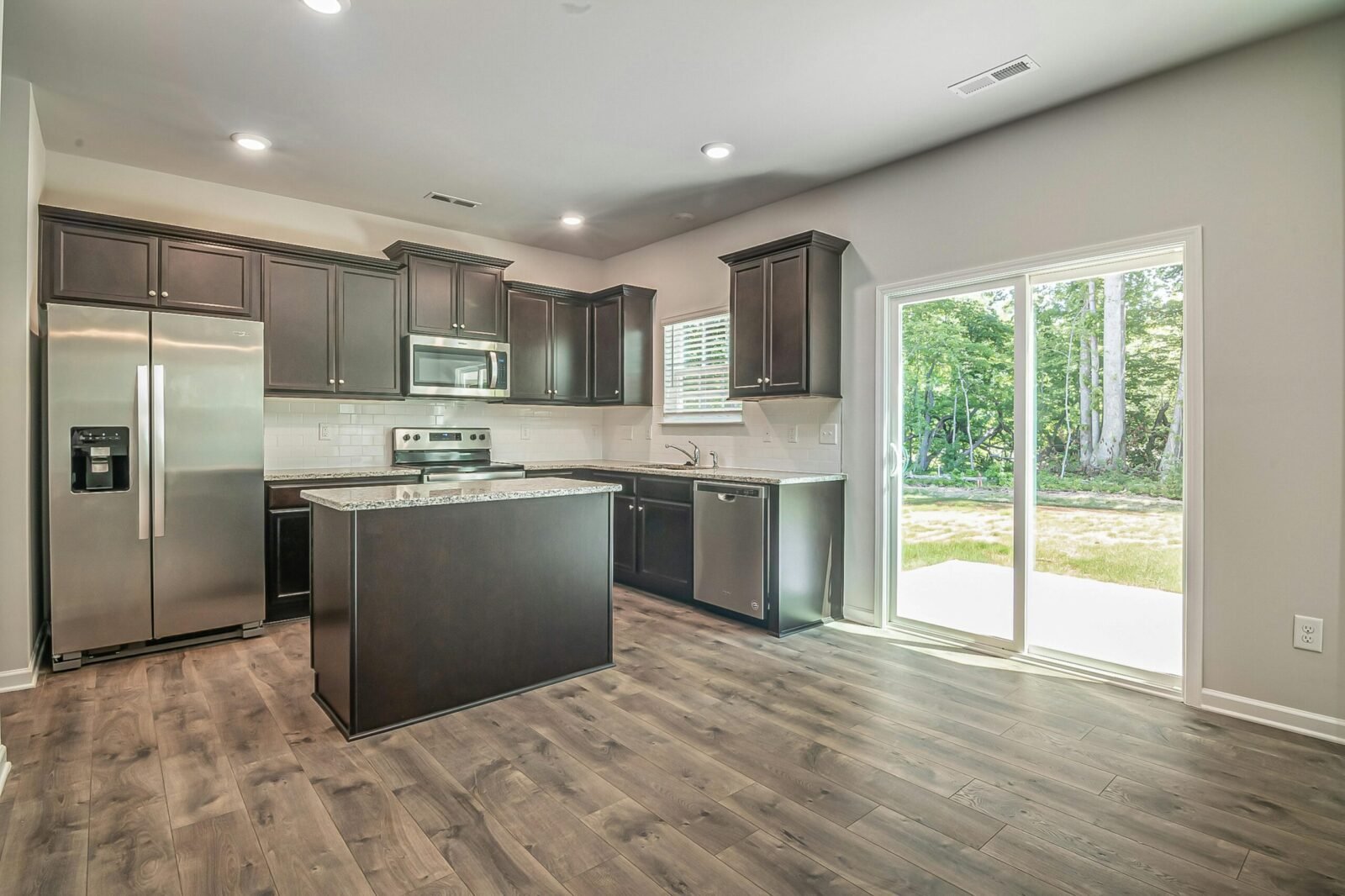 Spacious modern kitchen with stainless steel appliances and wooden floors.